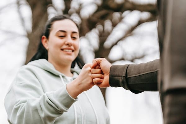 two people fist-bumping outdoors